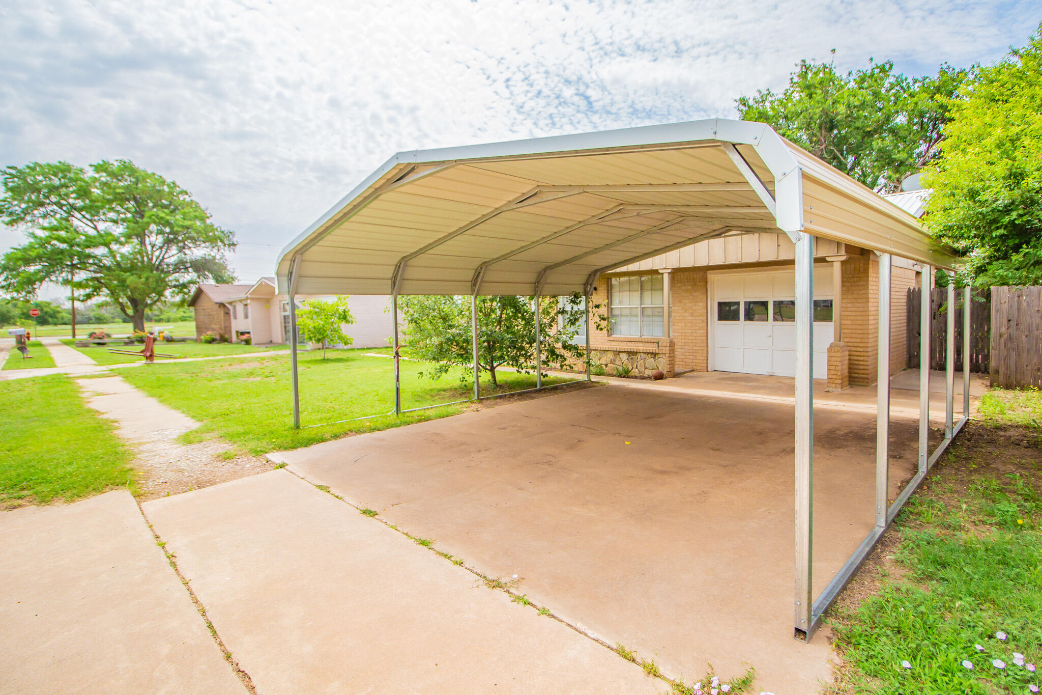 105 J B Avenue Floydada, TX 79235 - Photo 2 of 20 a view of yellow house with a big yard and potted plants