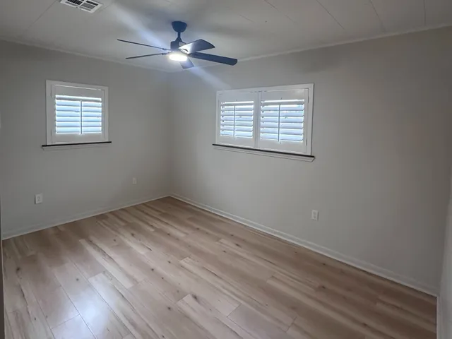 a view of empty room with wooden floor and fan