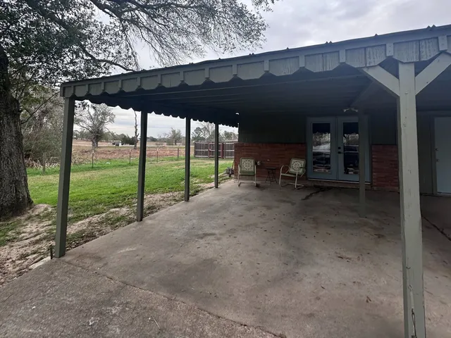a view of a porch with table and chairs under an umbrella with a small yard