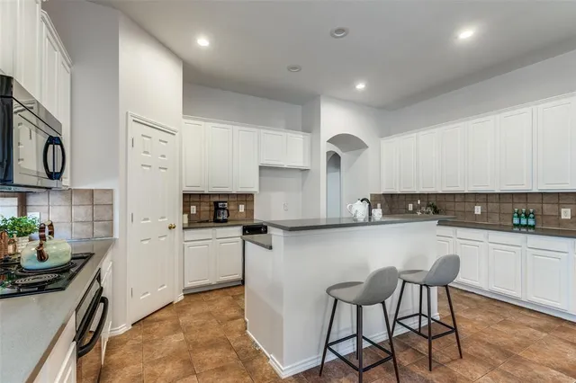 a kitchen with stainless steel appliances granite countertop a stove top oven a sink a counter space and cabinets