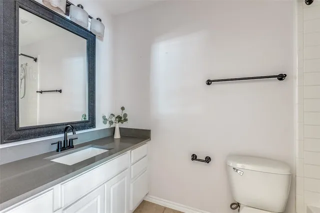 a bathroom with a granite countertop sink a toilet and a mirror