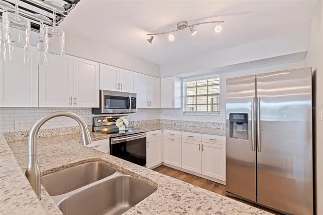 a kitchen with a sink stainless steel appliances and white cabinets