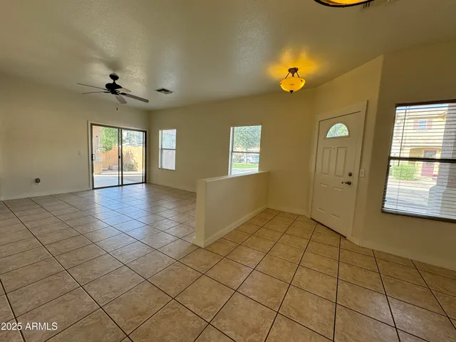 a view of an empty room with window and chandelier fan