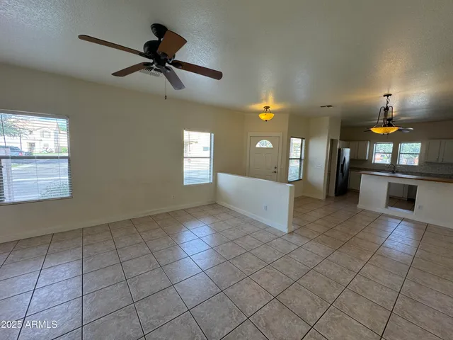 an empty room with windows and ceiling fan