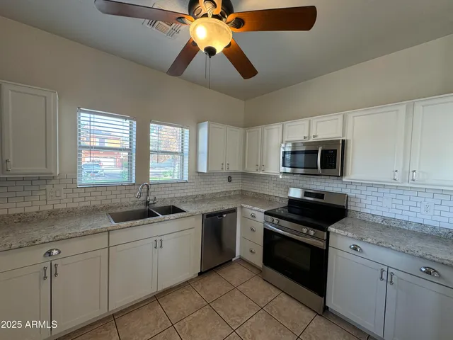 a kitchen with stainless steel appliances granite countertop a sink and a refrigerator