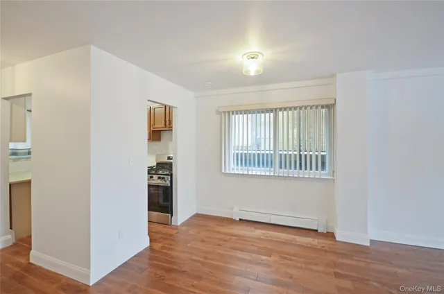 a view of an empty room with a window and wooden floor
