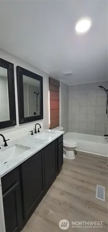 a bathroom with a double vanity sink toilet and mirror