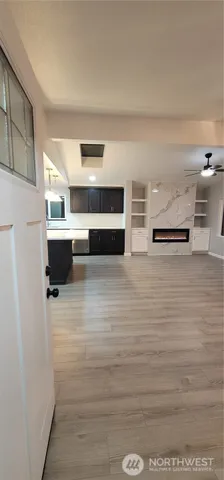 a view of kitchen and empty room with wooden floor