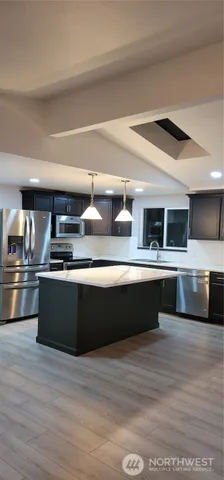 a kitchen with stainless steel appliances kitchen island granite countertop a stove and a refrigerator