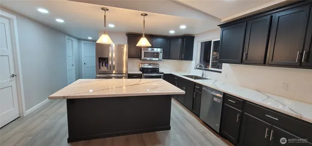 a kitchen with kitchen island a sink stainless steel appliances and cabinets