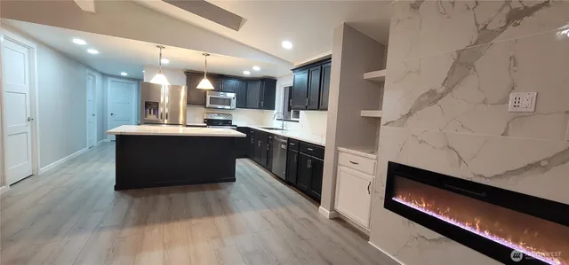 a kitchen with stainless steel appliances kitchen island granite countertop a stove top oven and sink