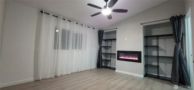 an empty room with wooden floor closet and windows