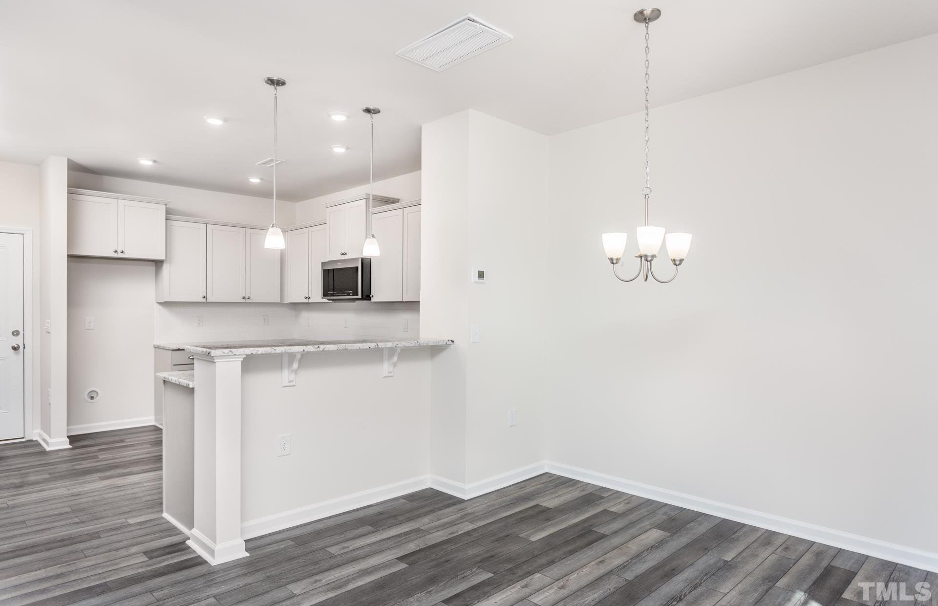 5714 Volos Avenue Raleigh, NC 27603 - Photo 9 of 20 a view of a kitchen with a microwave and wooden floor
