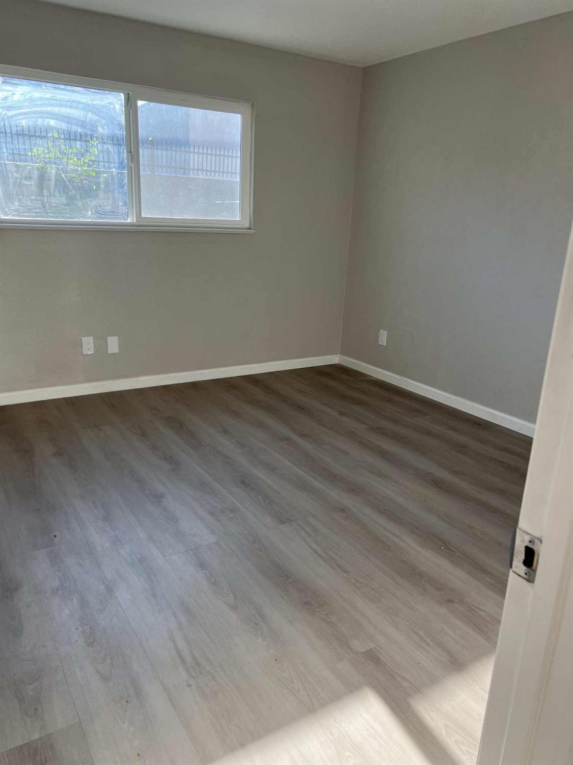 8603 Acapulco Way Stockton, CA 95210 - Photo 15 of 39 an empty room with wooden floor and windows