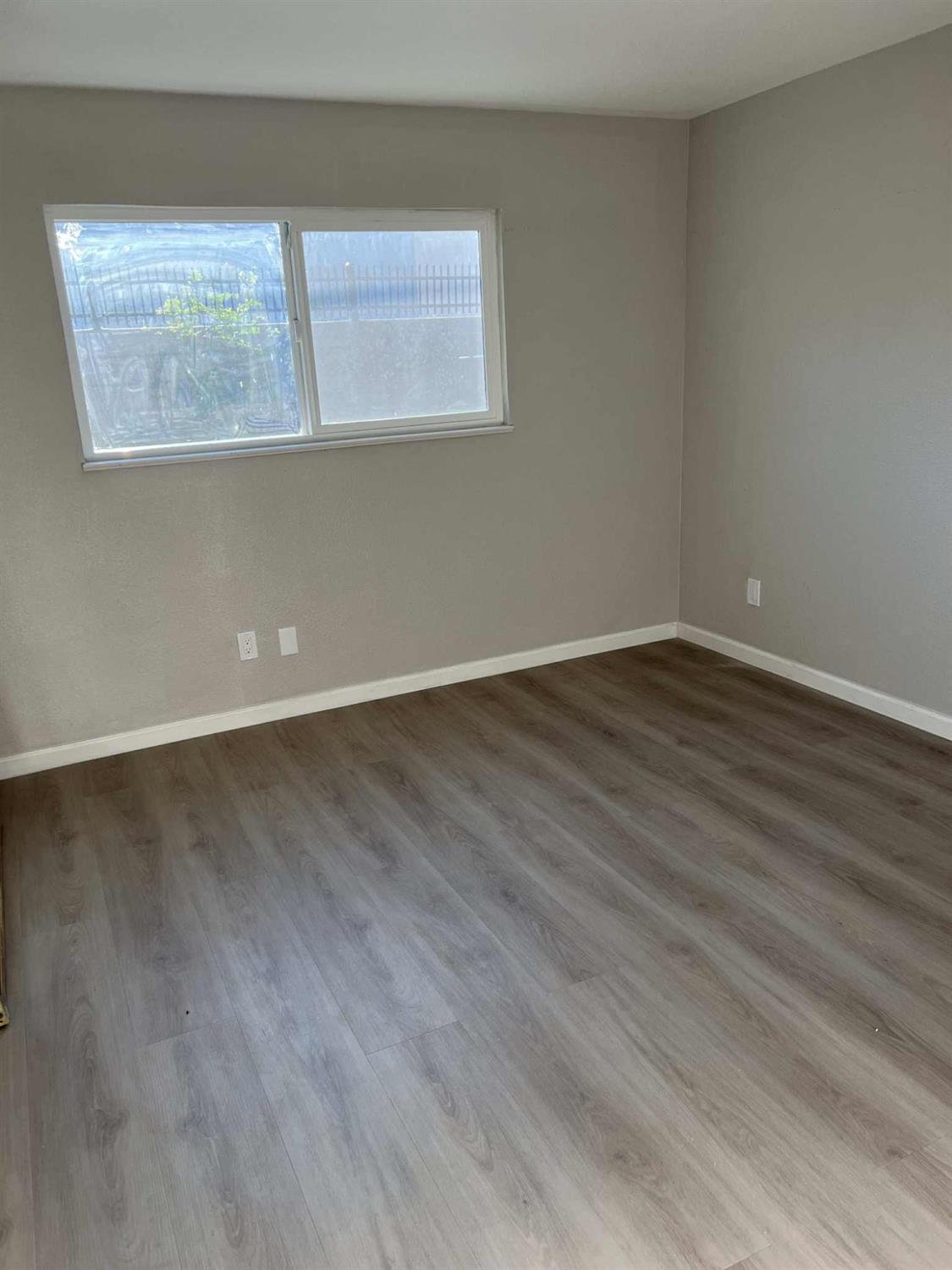 8603 Acapulco Way Stockton, CA 95210 - Photo 6 of 39 a view of an empty room with wooden floor and a window
