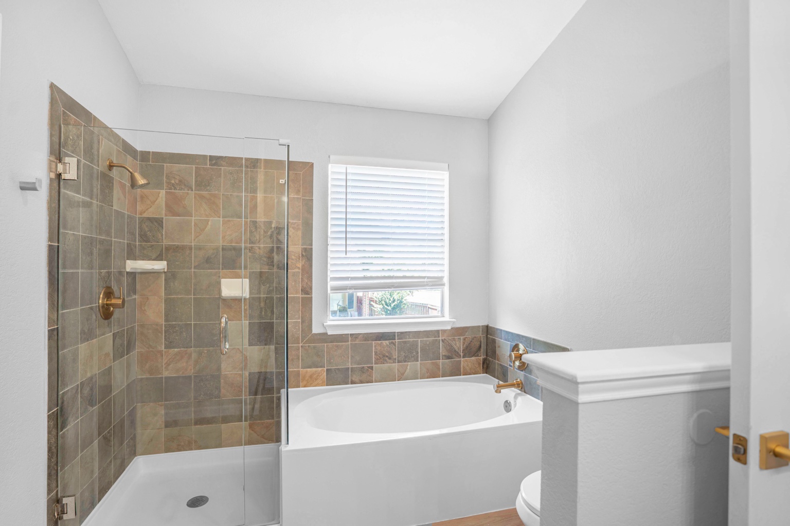 800 Smoke Signal Pass Pflugerville, TX 78660 - Photo 19 of 40 A well-lit bathroom features a glass-enclosed shower alongside a pristine bathtub, adorned with elegant tile accents.