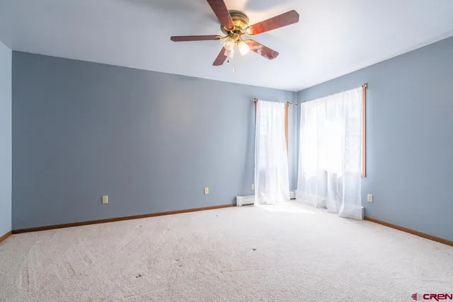 an empty room with a window and a fan