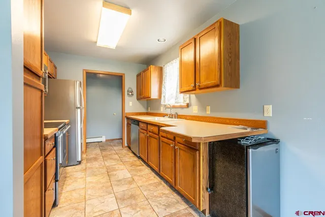 a utility room with stainless steel appliances granite countertop a sink and a refrigerator