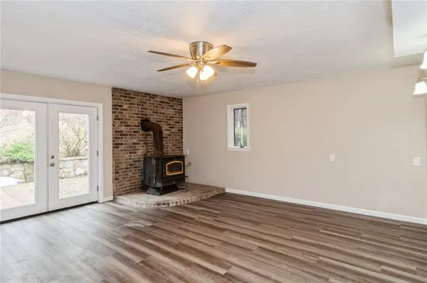 an empty room with wooden floor fan and windows