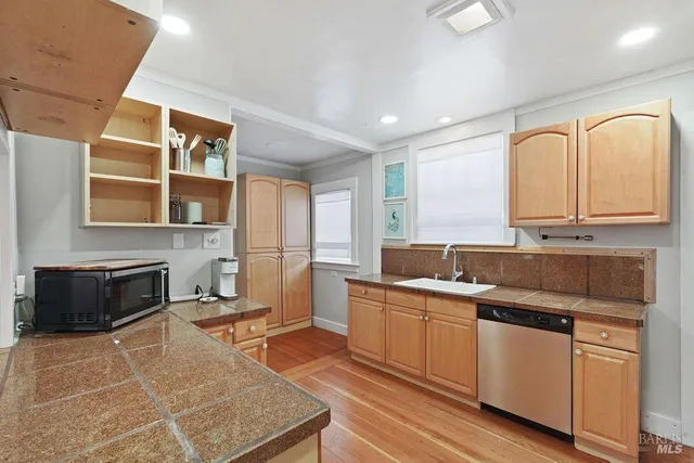 a kitchen with a refrigerator a sink dishwasher and a stove with wooden floor