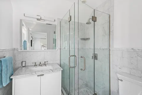 a bathroom with a granite countertop sink a toilet and shower