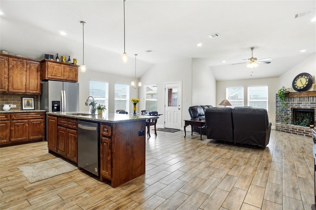 904 Avagail Avenue Springtown, TX 76082 - Photo 15 of 27 a kitchen with stainless steel appliances granite countertop a refrigerator a sink dishwasher a stove and a dining table with wooden floor