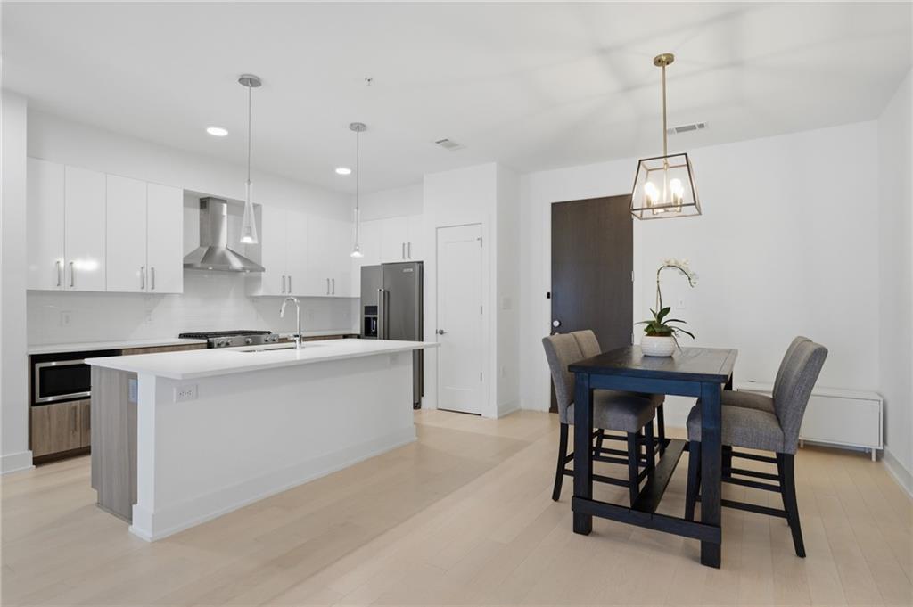 775 Juniper Street Northeast, Unit 322 Atlanta, GA 30308 - Photo 4 of 34 a kitchen with stainless steel appliances a dining table chairs and white cabinets