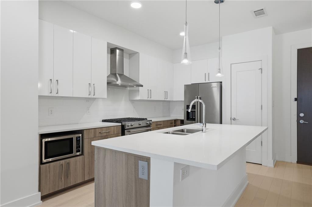 775 Juniper Street Northeast, Unit 322 Atlanta, GA 30308 - Photo 5 of 34 a kitchen with stainless steel appliances a stove a sink a refrigerator and white cabinets