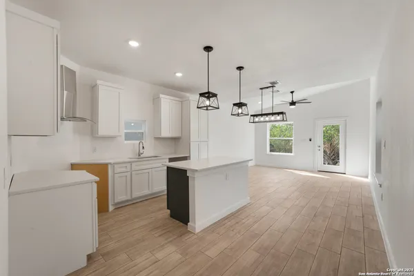 a kitchen with kitchen island wooden floors white cabinets and stainless steel appliances
