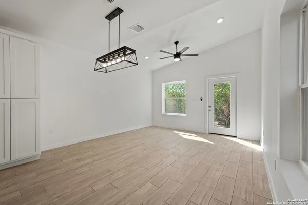 an empty room with windows and ceiling fan