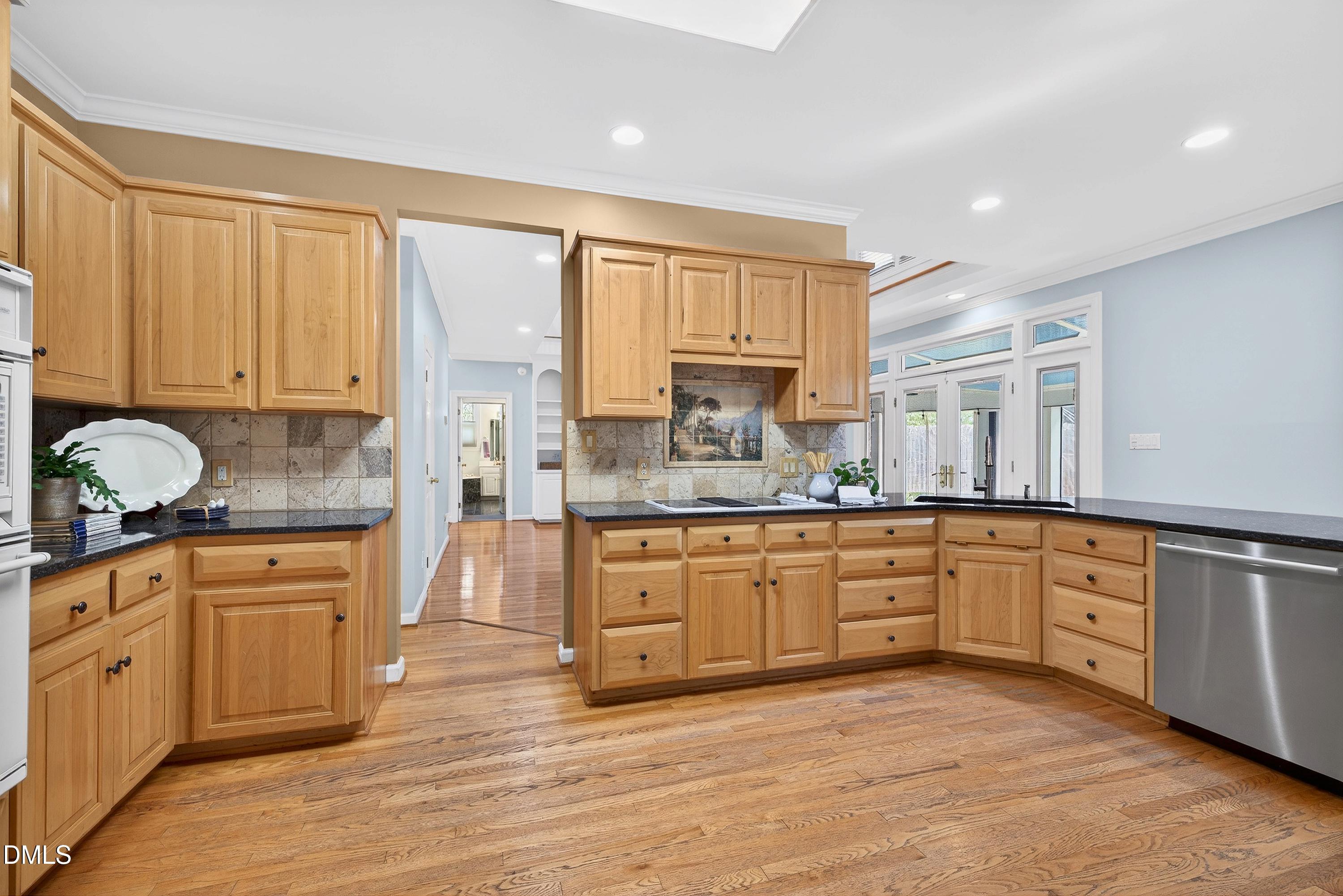 2217 Moss Point Lane Raleigh, NC 27606 - Photo 21 of 70 a large kitchen with granite countertop a stove top oven a sink a window and white cabinets