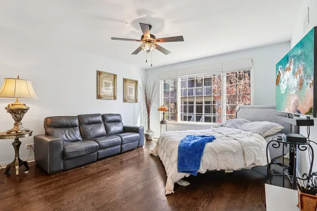 a bedroom with a bed couches and a flat tv screen on dresser