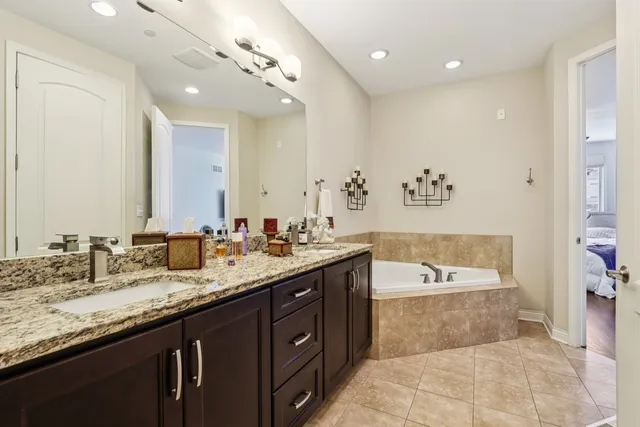 a spacious bathroom with a granite countertop double vanity sink a mirror and a bathtub