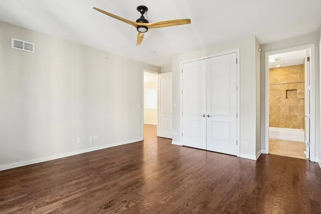 an empty room with wooden floor closet and windows