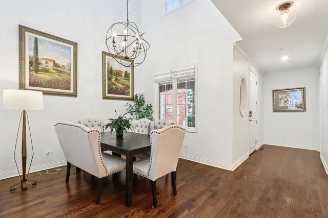 a dining room with wooden floor a chandelier a wooden table and chairs