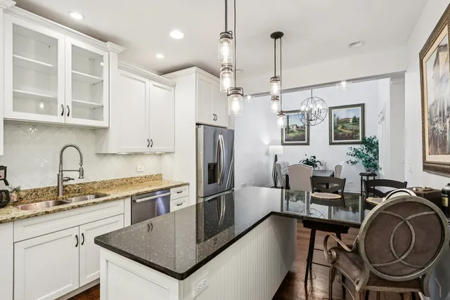 a kitchen with granite countertop a table chairs stove and refrigerator