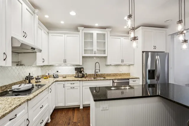 a kitchen with stainless steel appliances granite countertop a refrigerator sink and white cabinets