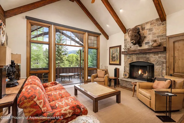 a living room with furniture a fireplace and floor to ceiling windows