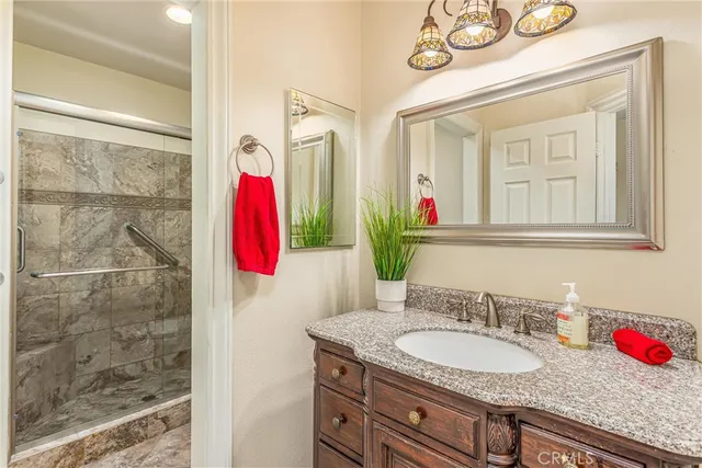 a bathroom with a granite countertop shower a sink and a mirror