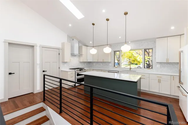 a kitchen with a stove a sink a chandelier and wooden floors