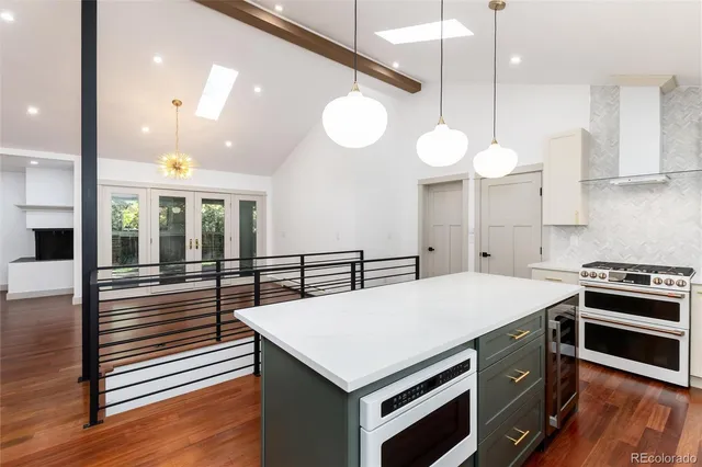 a kitchen with a stove a refrigerator a sink and white cabinets with wooden floor