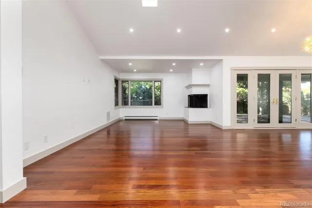 an empty room with wooden floor and windows