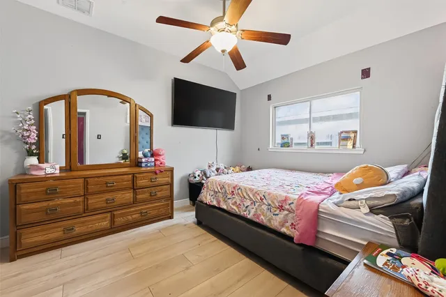 a bedroom with a bed and a flat tv screen on dresser