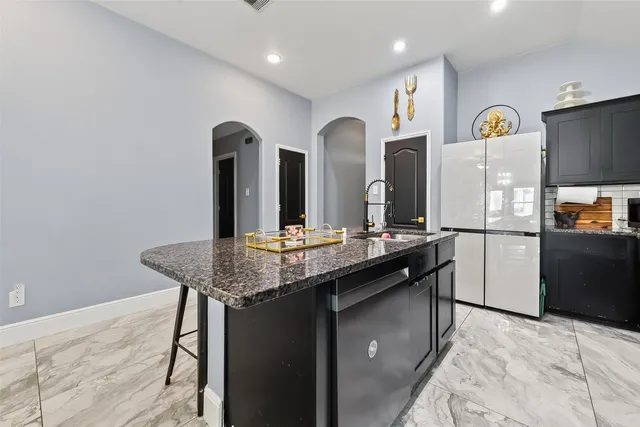 a kitchen with stainless steel appliances kitchen island granite countertop a refrigerator a sink and dishwasher with wooden floor