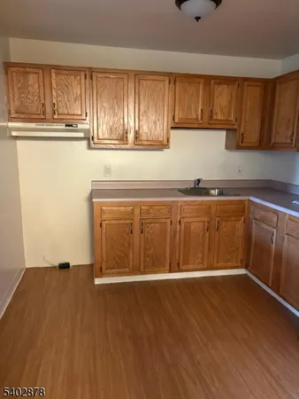 a view of a kitchen with wooden floor and cabinets