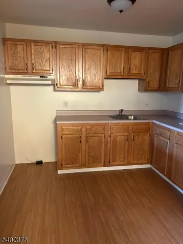 a view of a kitchen with wooden floor and cabinets