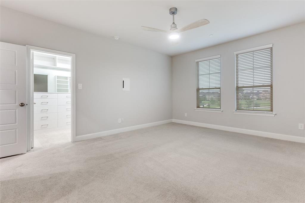 1888 Strand Street Dallas, TX 75234 - Photo 7 of 13 Plush carpeted room featuring a ceiling fan with integrated lighting, two windows with blinds, and a doorway opening to a custom closet with built-in shelving and drawers