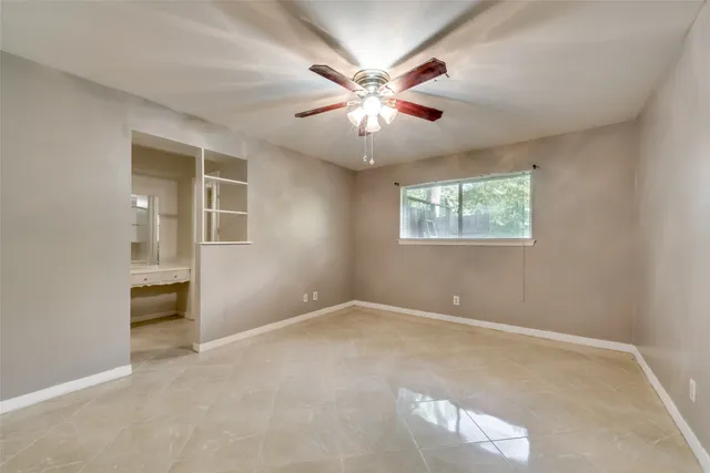 an empty room with windows and chandelier fan
