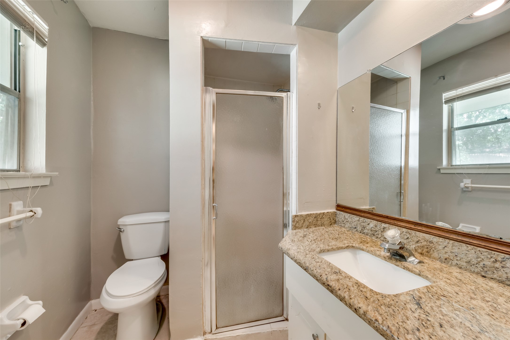 1522 Baggett Lane, Unit A Houston, TX 77055 - Photo 14 of 29 a bathroom with a granite countertop toilet a sink and a mirror