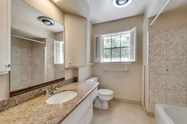 a bathroom with a granite countertop sink toilet and shower